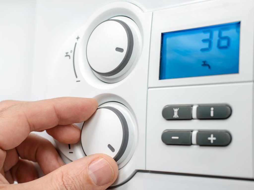Plumber Using A Boiler Control Panel